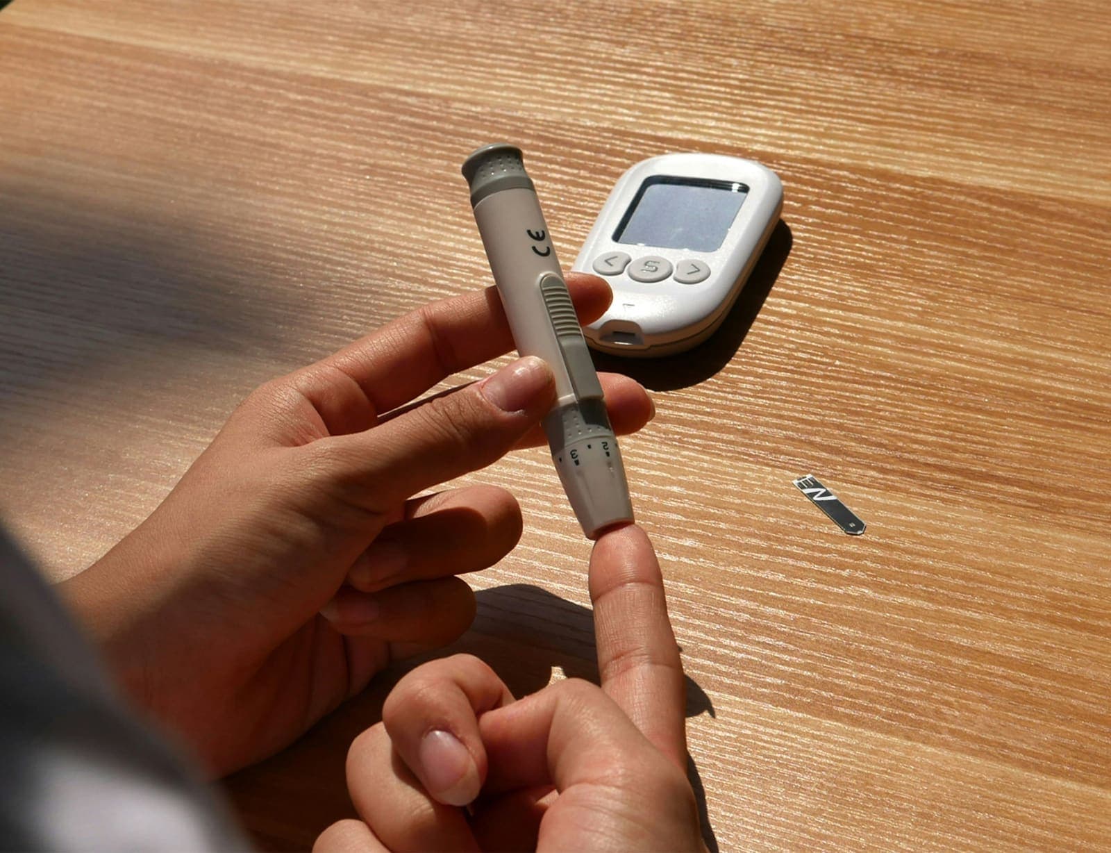 Hände beim Blutzuckermessen mit Stechhilfe und Messgerät