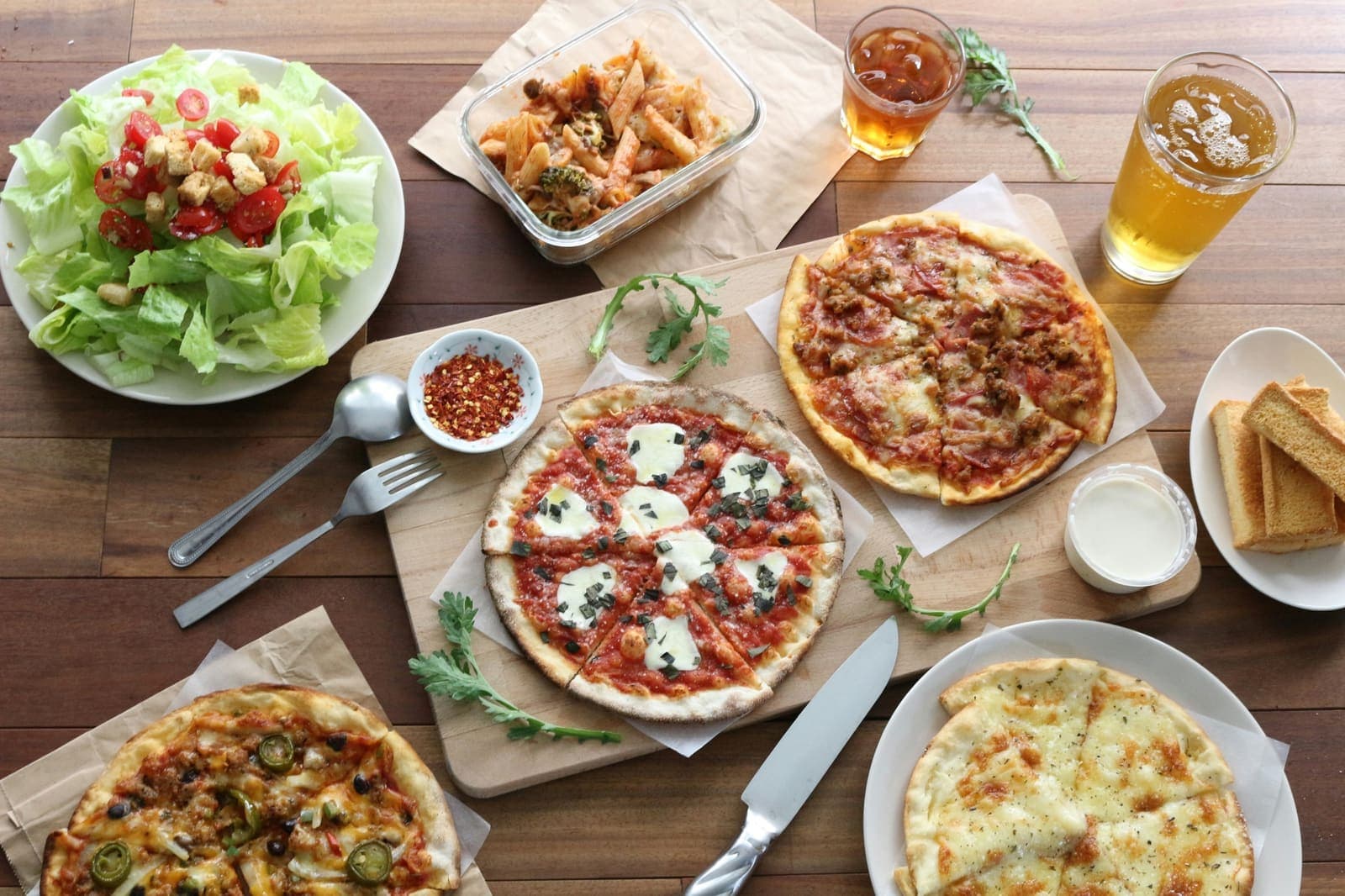 Tisch mit Pizza, Salat und Nudelauflauf