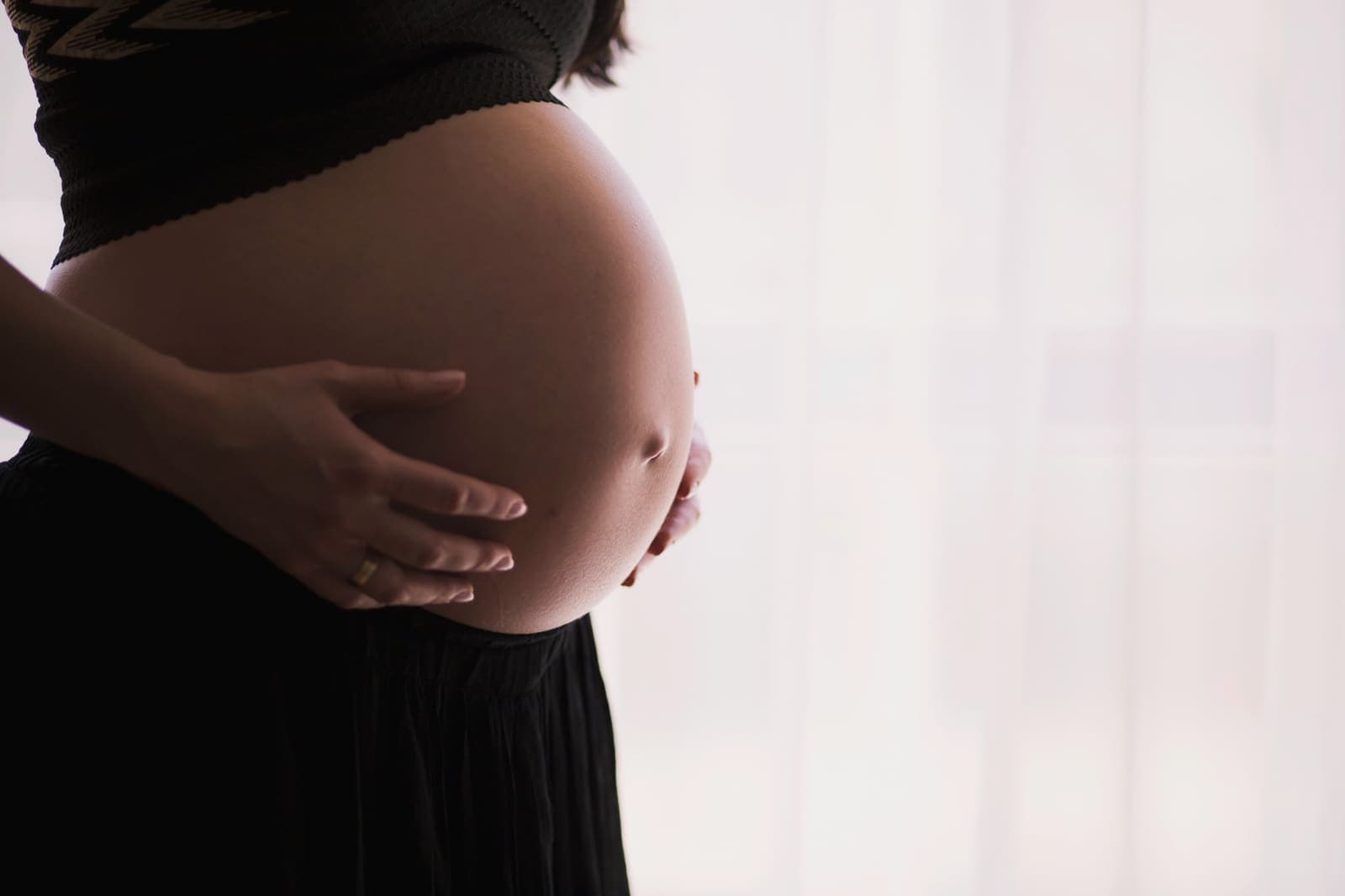Schwangere legt die Hände an ihren Bauch
